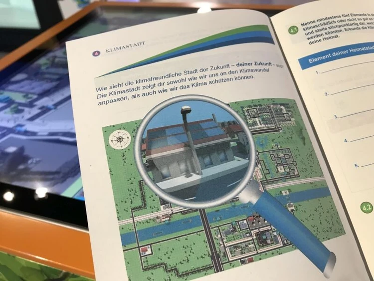 Eine Lupe ist in einem ge&ouml;ffneten Heft zu sehen.