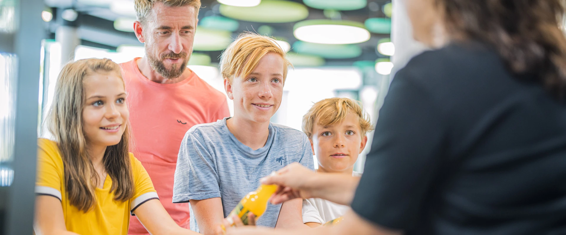 Drei Kinder und ein Mann werden an der Theke im Bistro bedient.