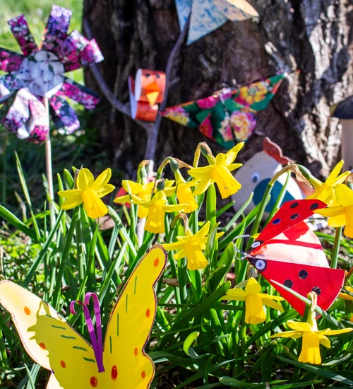 Auf dem Bild sind gelbe Narzissen zwischen gebastelten Fr&uuml;hlingsdekorationen zu sehen.