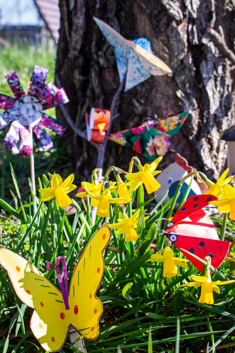 Auf dem Bild sind gelbe Narzissen zwischen gebastelten Fr&uuml;hlingsdekorationen zu sehen.